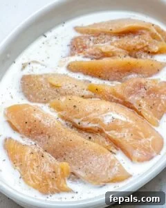 Chicken tenders soaking in a bowl of marinade
