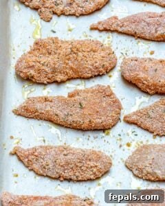 Breaded chicken tenders ready for baking on a sheet pan