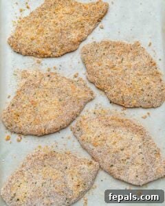 Golden Baked Chicken Cutlets 18 breaded chicken cutlets before baking, placed on a sheetpan.