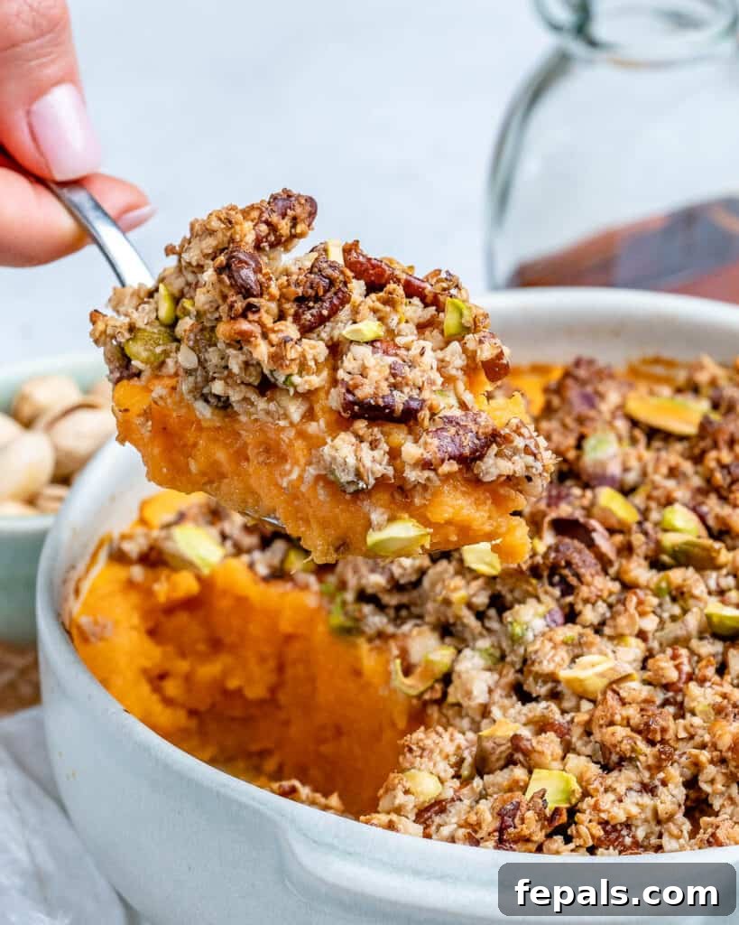 hand holding a spoonful of sweet potato casserole over a dish