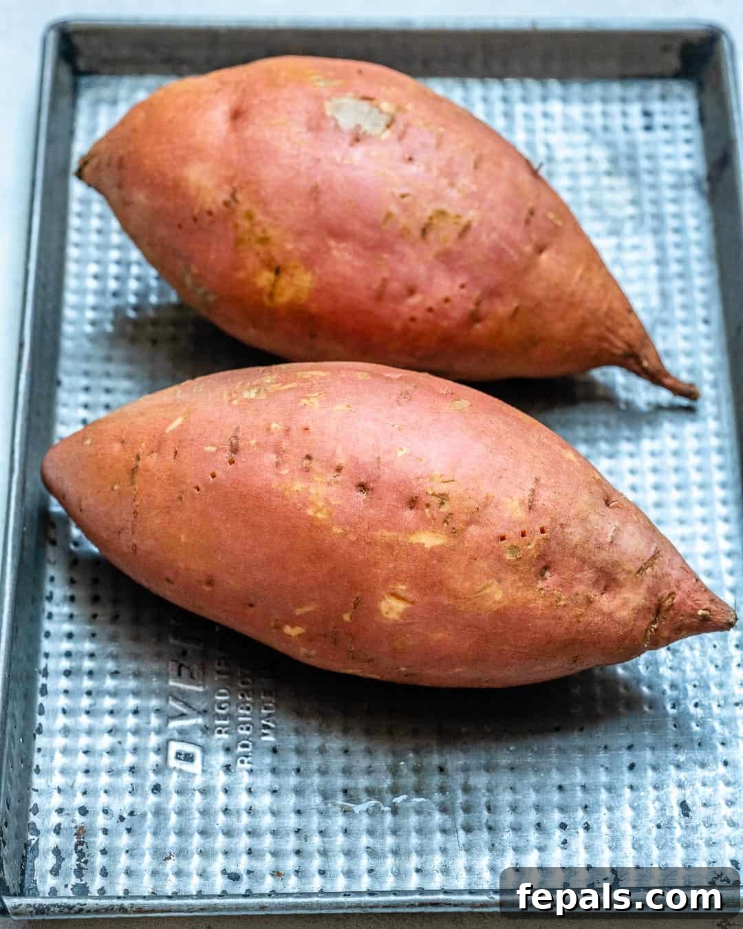 Ultimate Twice-Baked Sweet Potatoes 4 Two whole sweet potatoes, unbaked, resting on a sheet pan, ready for the first bake.