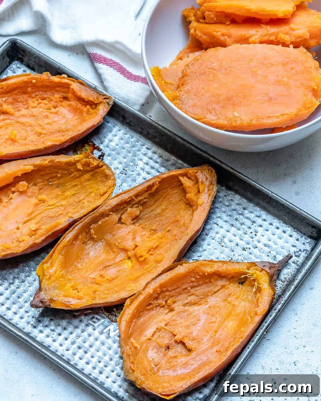 Ultimate Twice-Baked Sweet Potatoes 5 Baked and hollowed sweet potato halves, neatly arranged on a sheet pan, showcasing their perfectly cooked skins and scooped-out interiors.