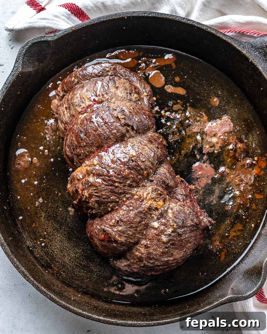 Aromatic Garlic Beef Tenderloin 4 Seared beef tenderloin in a black skillet.