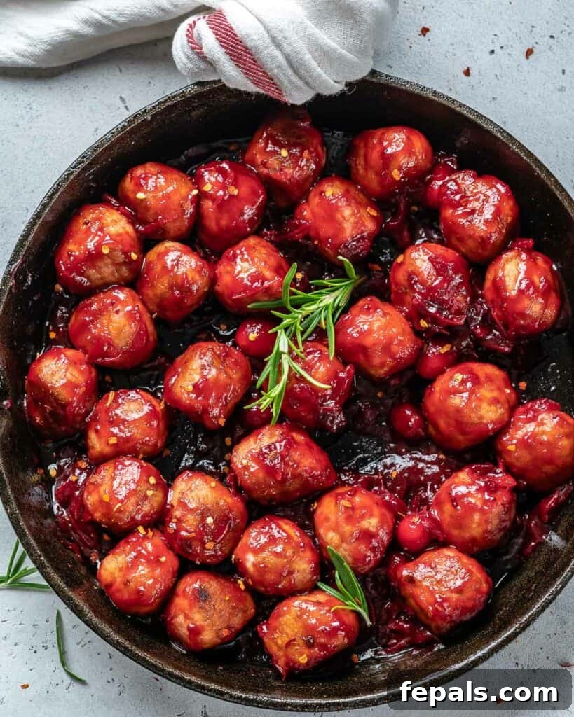 top view of cooked chicken meatballs drenched in cranberry sauce in a black skillet