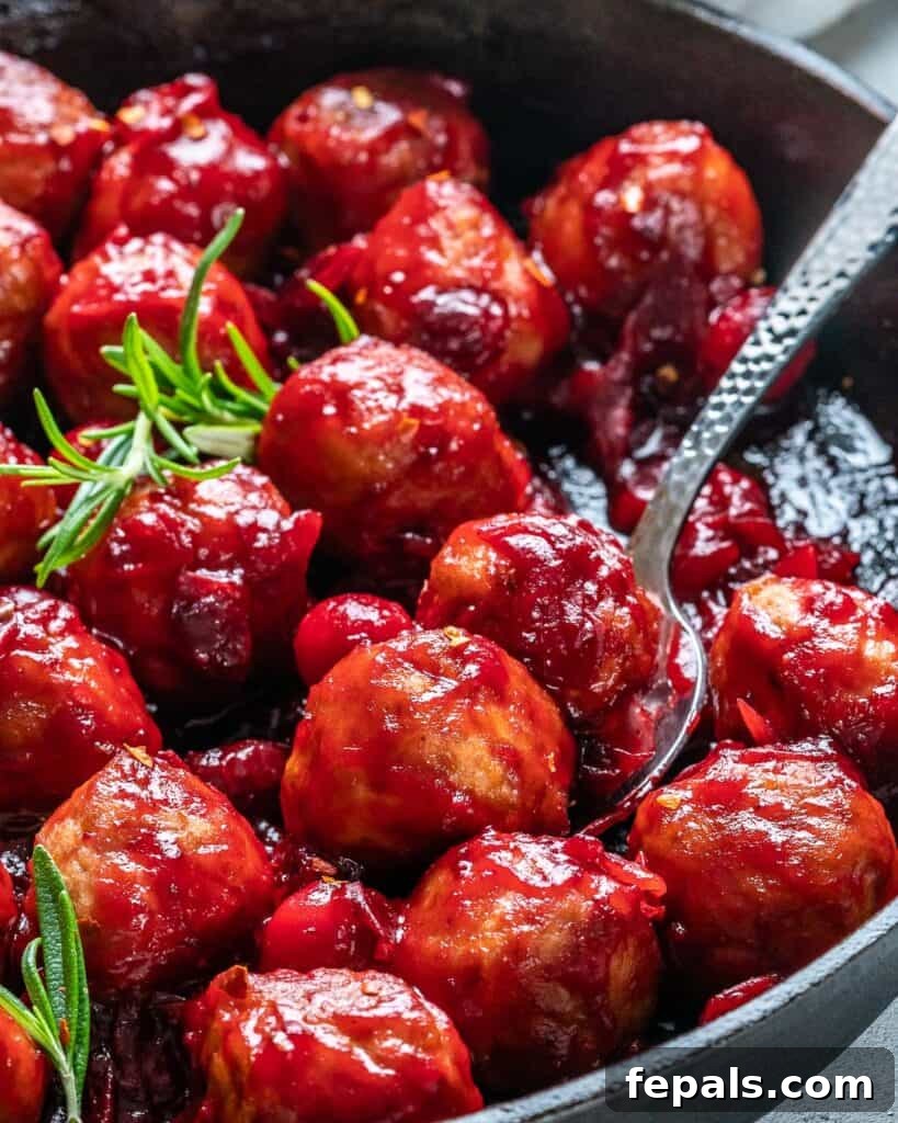 spoon grabbing a couple of cranberry meatballs from the skillt