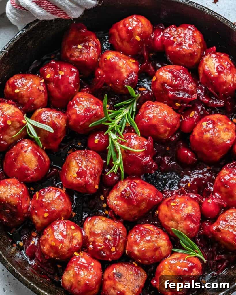 cooked chicken meatballs in cranberry sauce on a black skillet