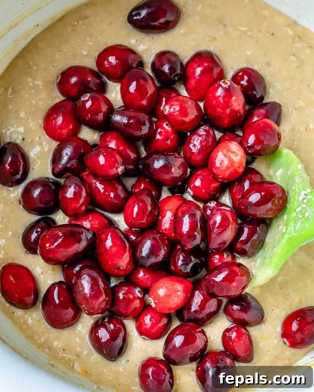 Zesty Cranberry Orange Loaf 5 Fresh cranberries being gently folded into the bread batter in a mixing bowl.