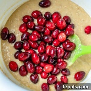 Folding fresh cranberries into the prepared bread batter.