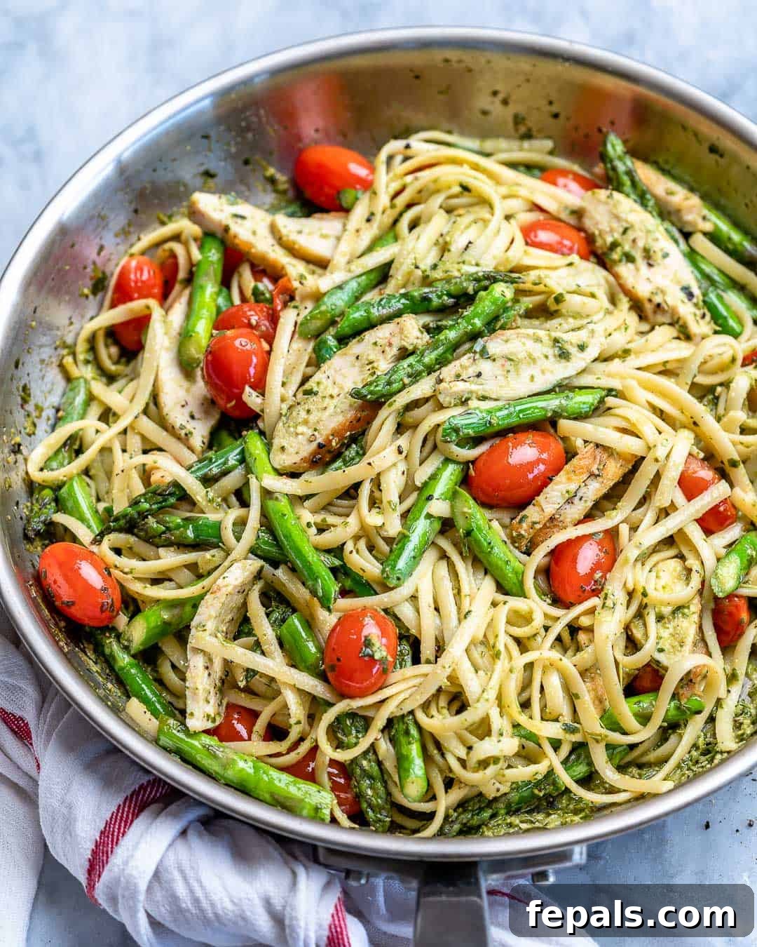Side view of a generous serving of Asparagus Pesto Chicken Pasta in a pan, highlighting the vibrant colors and rich sauce.