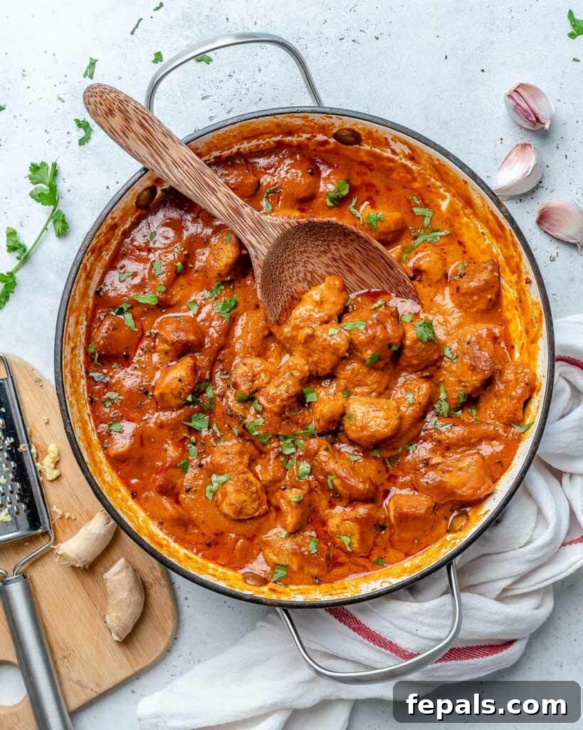 Quick & Creamy Butter Chicken 2 top view of Indian butter chicken in a pan with wooden spoon in pan