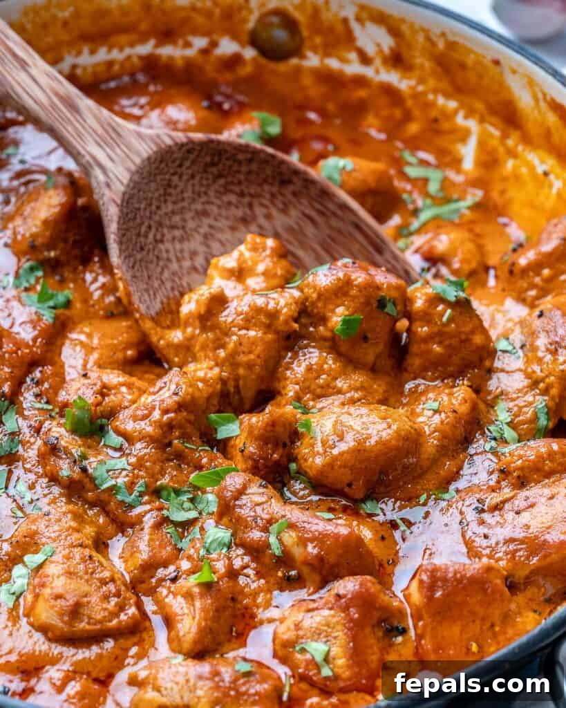 Quick & Creamy Butter Chicken 3 close up view of butter chicken in a pan with spoon grabbing some topped with fresh cilantro