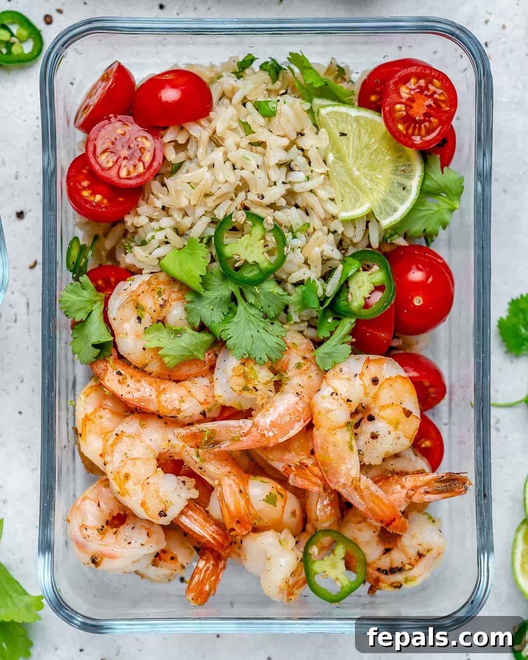 Savory Garlic Shrimp Meal Prep 2 A vibrant meal prep bowl featuring golden sautéed garlic lime shrimp alongside fluffy cilantro lime rice and a sprinkle of fresh chopped tomatoes and cilantro.