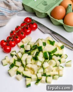 Chopped zucchini and tomatoes on a sheet pan.