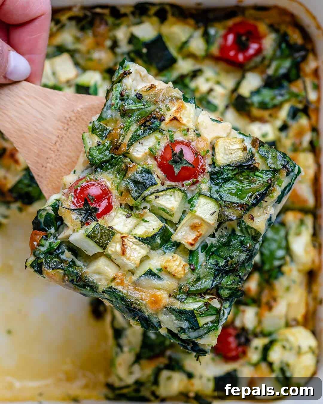 A slice of crustless quiche on a spatula, showcasing its fluffy texture and vibrant ingredients.