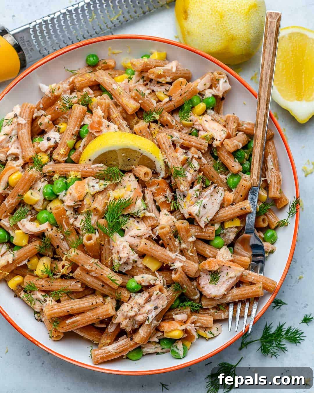 Healthy pasta salad recipe with peas, corn, and salmon in a serving bowl