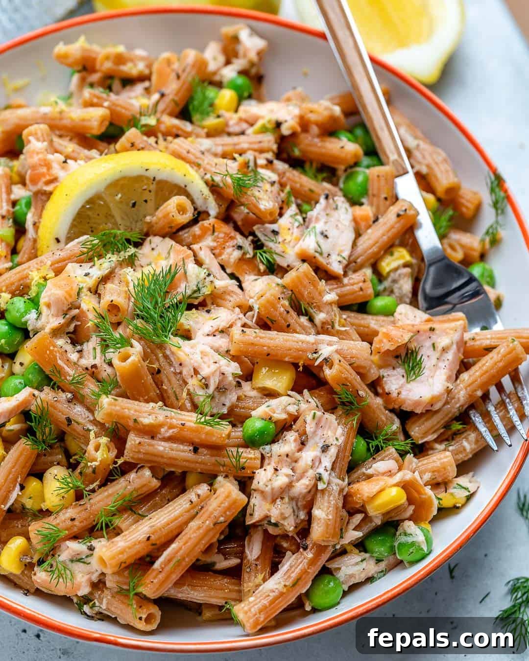 Close-up of salmon and pasta recipe with peas and corn, showcasing vibrant colors