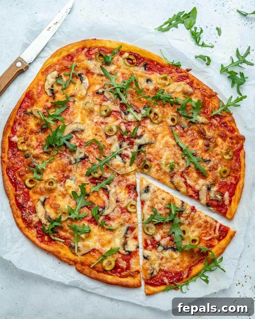 Top view of a freshly baked, round low-carb pizza on parchment paper, with one slice carefully cut out, showcasing its crispy edge and delicious toppings.