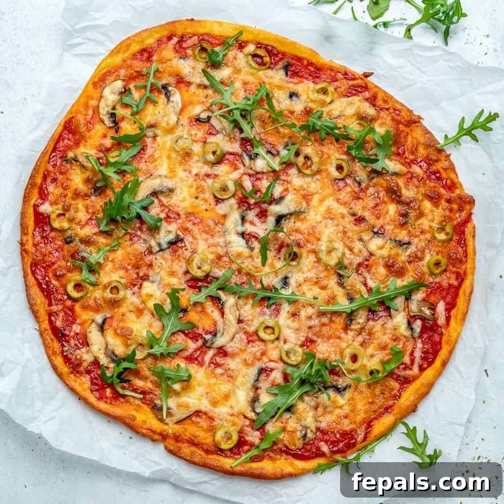 Top view of a baked thin-crust pizza generously topped with melted cheese and vibrant green sliced olives, ready to be served.