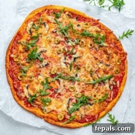 Top view of a baked thin-crust pizza topped with cheese and sliced green olives