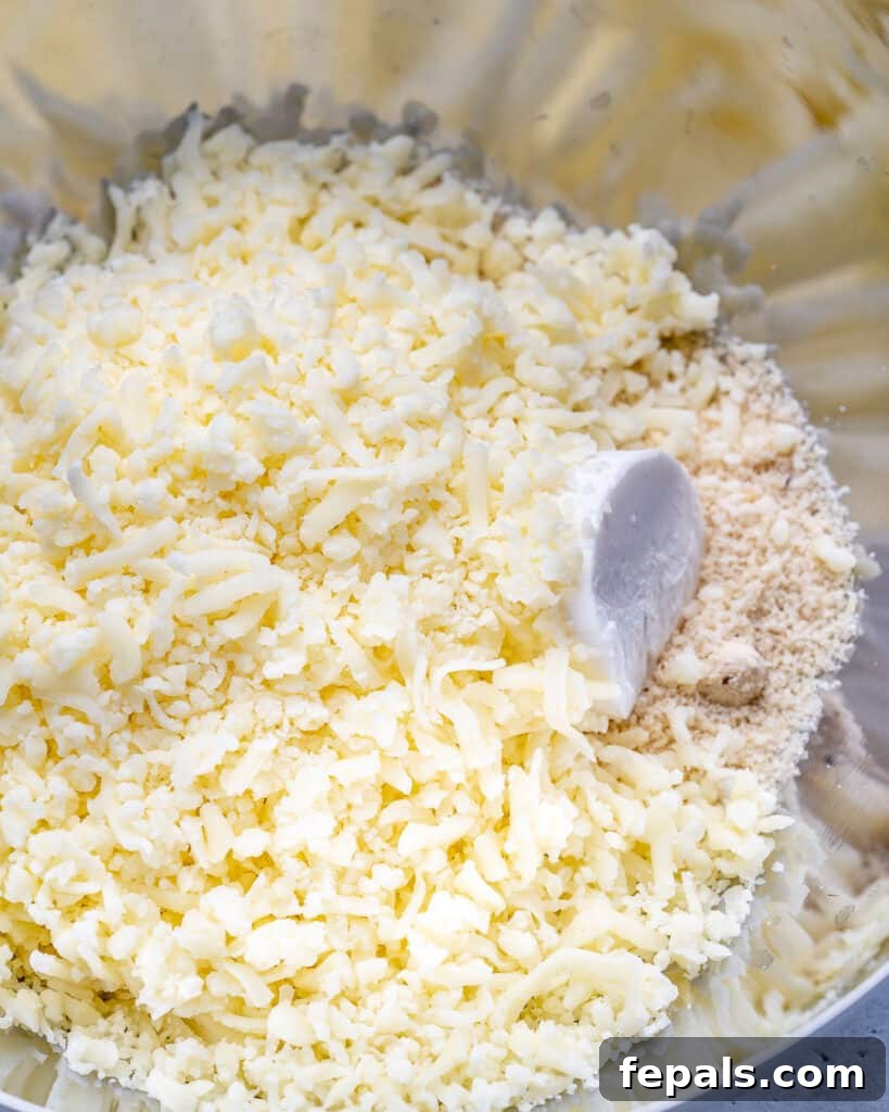 Almond flour, soft cream cheese, and grated mozzarella cheese are combined in a mixing bowl, ready for microwave heating to form the fathead dough.