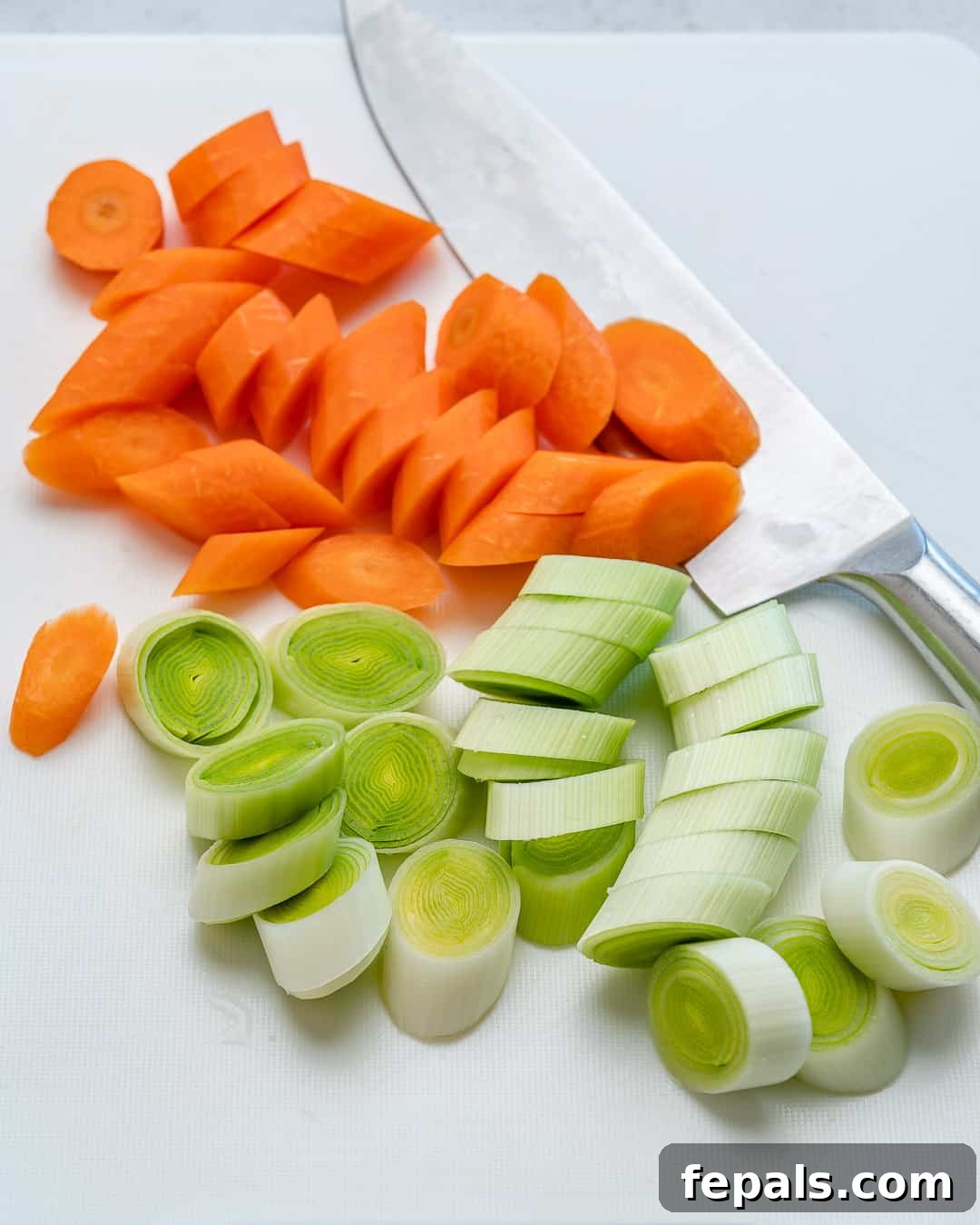 Nourishing Vegan Lentil Soup 4 Freshly chopped leeks and carrots artfully arranged on a wooden cutting board, ready for simmering in the soup.