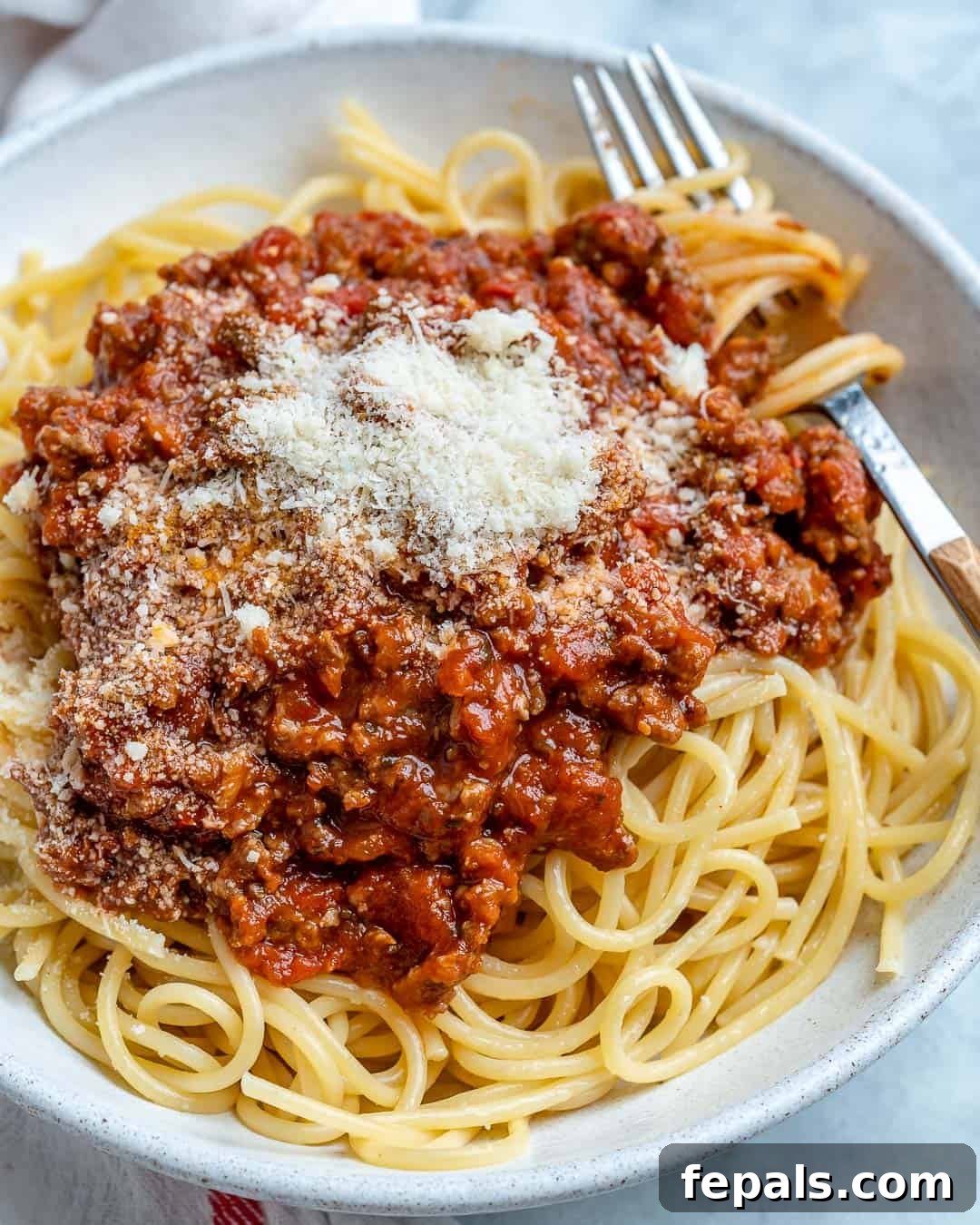 Homemade Meat Sauce served over cooked spaghetti with parmesan cheese on top