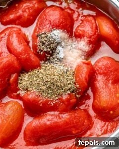 Seasonings added on canned tomatoes in a pan.