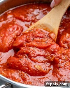 Seared and cooked tomatoes and herbs in a pan.