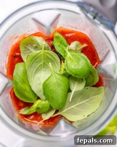 Tomato sauce and fresh basil added into a blender.