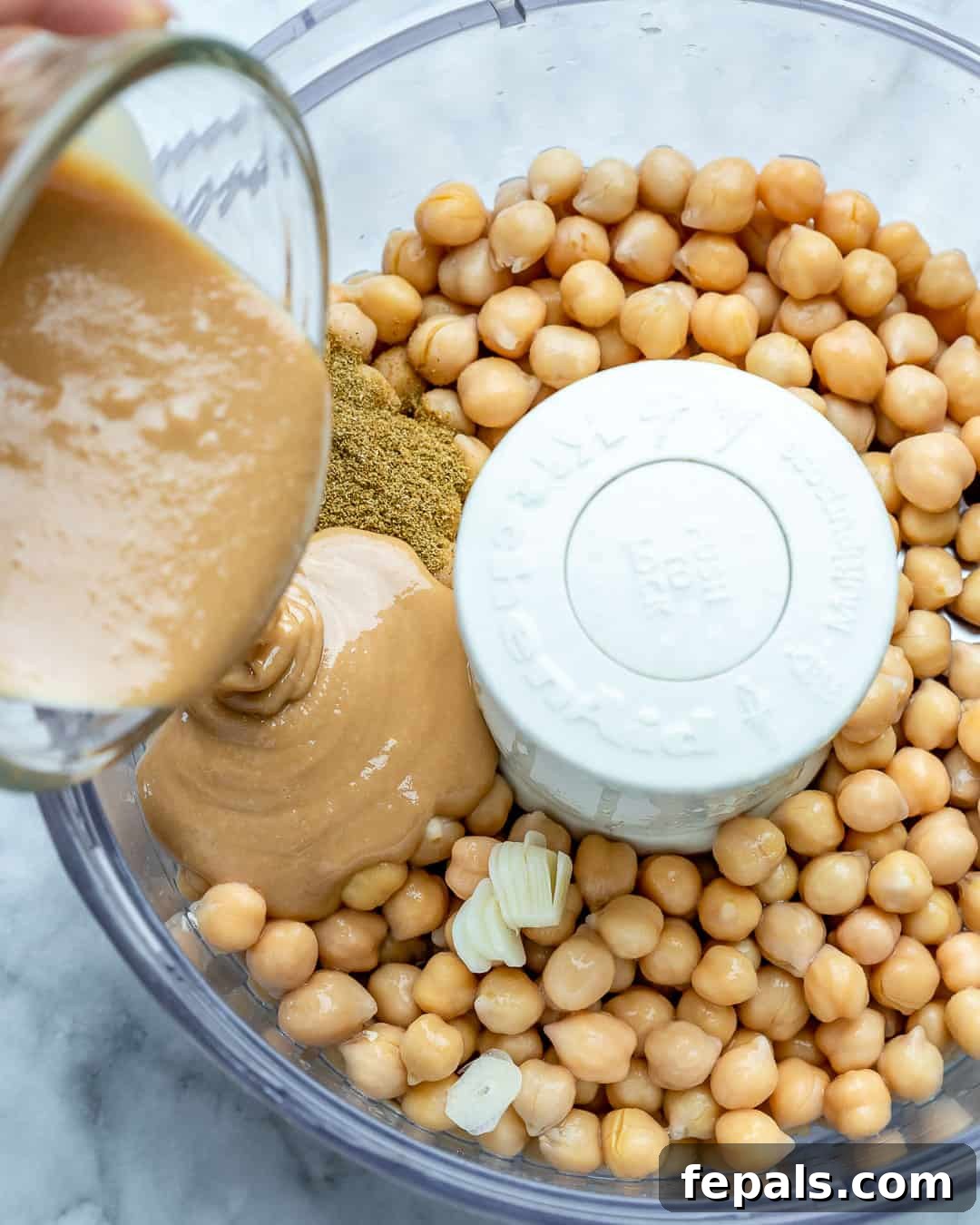 Simple Steps to Creamy Homemade Hummus 6 Chickpeas, tahini, lemon juice, garlic, and water being added to a high-powered blender.