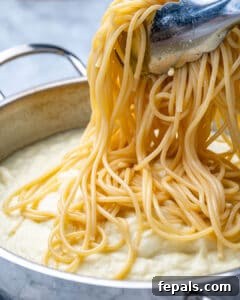 Healthy and Delicious Cauliflower Alfredo Sauce 20 spaghetti being added over alfredo sauce in pan