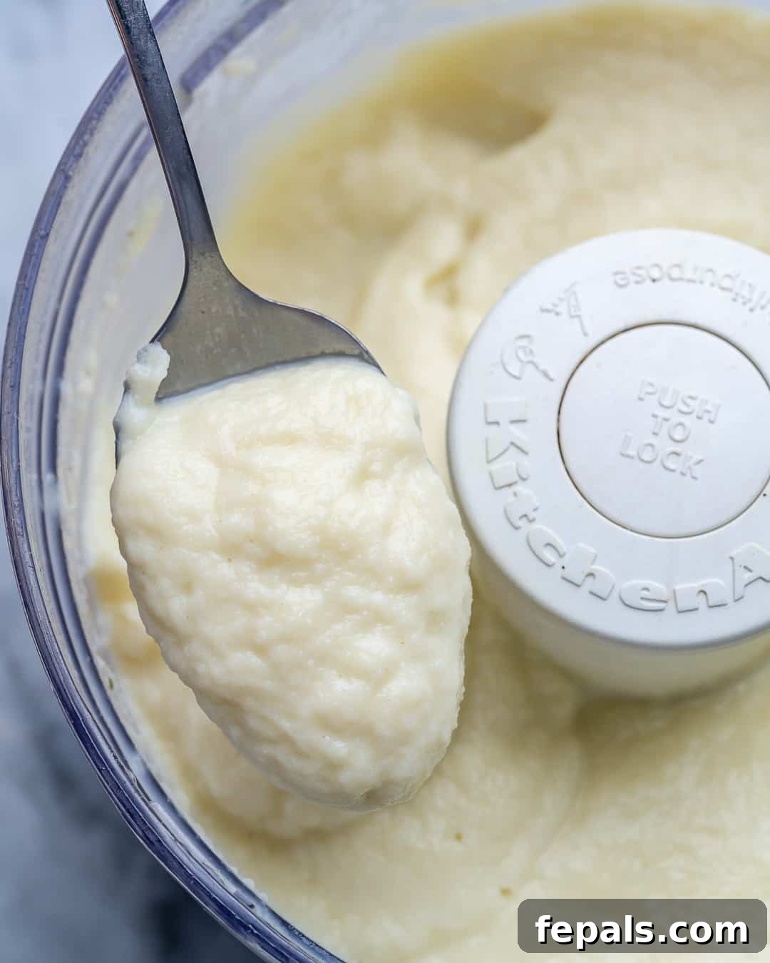 Healthy and Delicious Cauliflower Alfredo Sauce 7 Blended cauliflower Alfredo sauce in a food processor with a spoonful of the sauce ready to be tasted