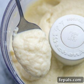 blended cauliflower sauce in food processor with a spoonful of the sauce