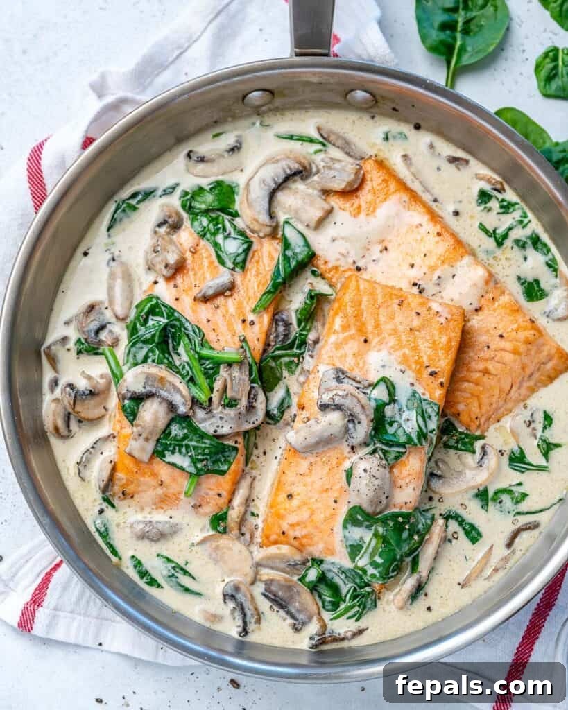 Effortless Salmon Florentine 2 top view of a silver skillet with 3 salmon filets in a creamy white mushroom and spinach sauce