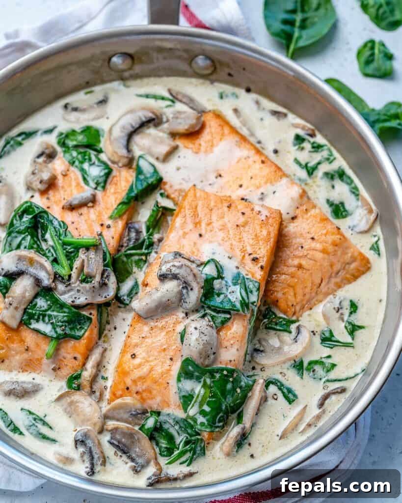 Effortless Salmon Florentine 3 side view of 3 cooked salmon filets in a creamy mushroom and spinach sauce