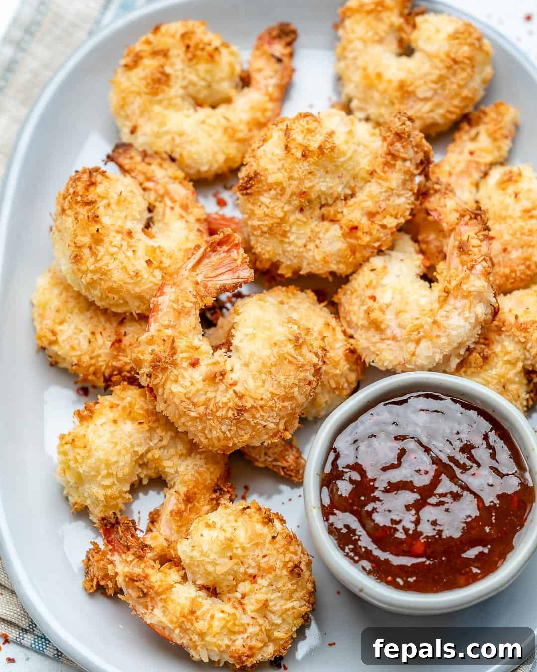 a large oval dish with coconut shrimp and a side of dipping sauce next to them
