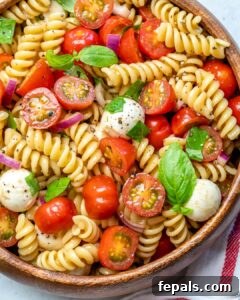 pasta salad in a round round bowl made with fresh chopped tomatoes, fresh mozzarella balls, and fresh basil.