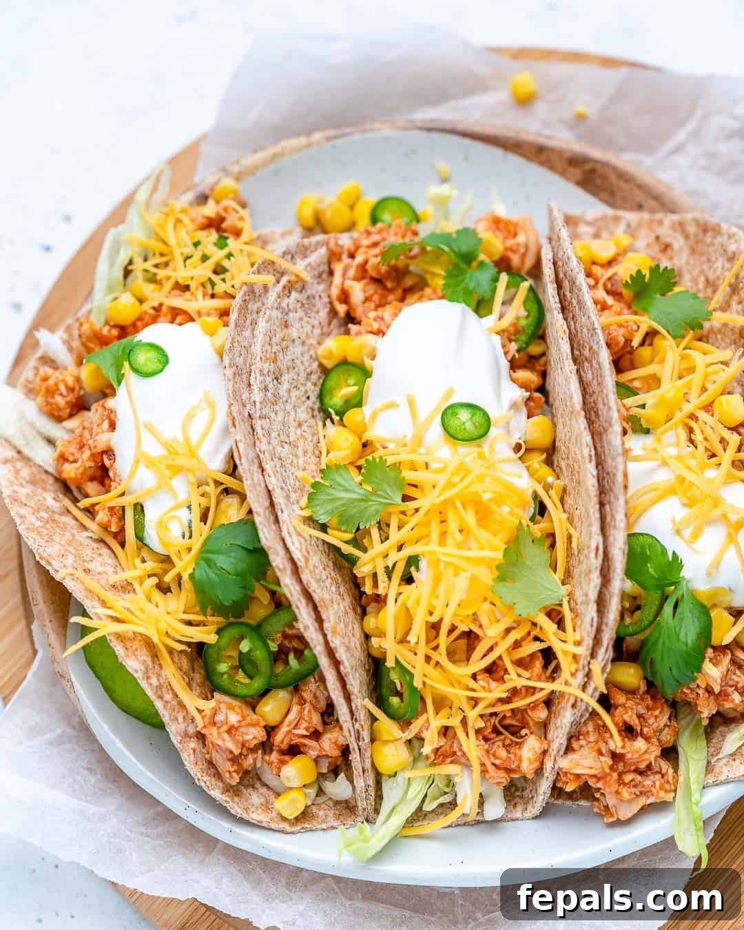 A vibrant close-up of a prepared buffalo chicken taco, showcasing shredded chicken, fresh lettuce, and a drizzle of sauce, ready to be enjoyed.