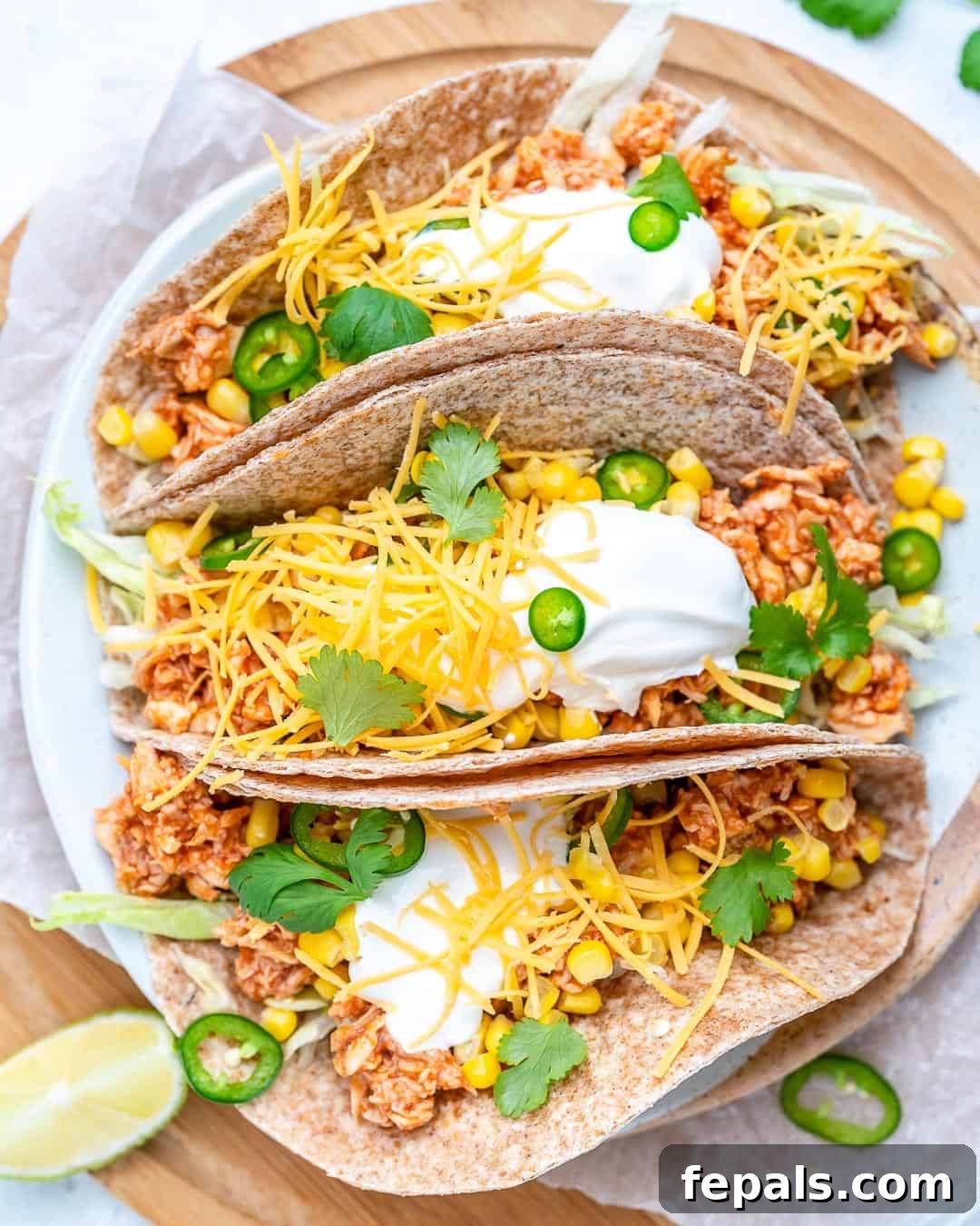 Three perfectly assembled buffalo chicken tacos lined up, showcasing the rich filling and fresh toppings.