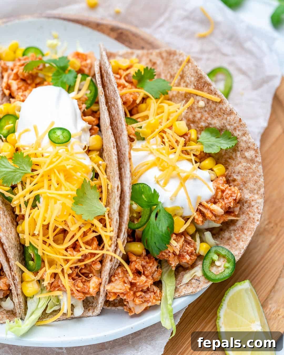Two Buffalo Chicken Tacos on a plate with lime wedges and fresh cilantro, highlighting the vibrant colors and appealing presentation.