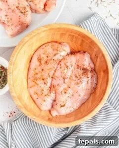 Chicken breast marinated in a bowl.
