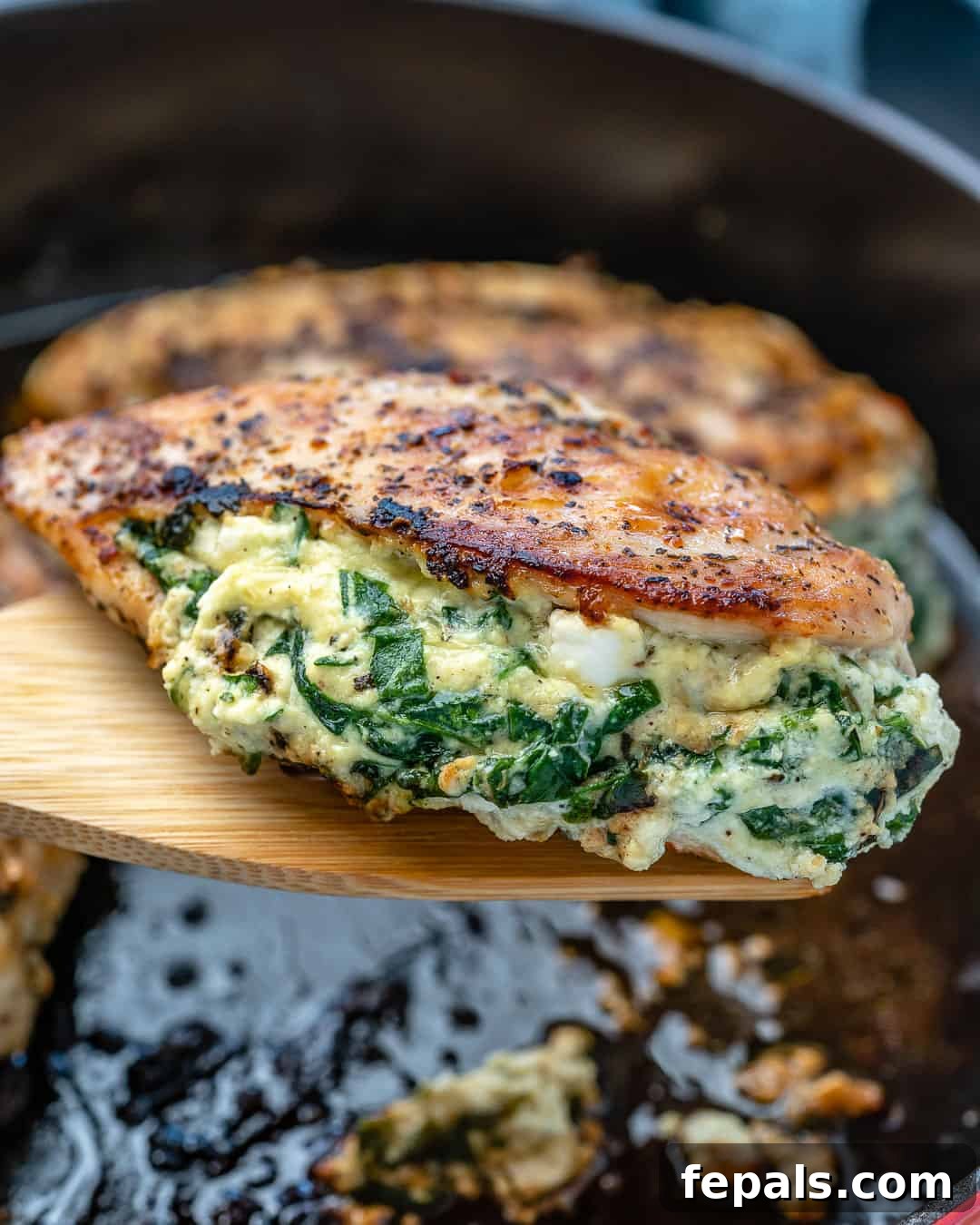 Creamy Spinach and Cheese Stuffed Chicken 10 A single stuffed chicken breast perfectly golden brown on a wooden serving spoon.