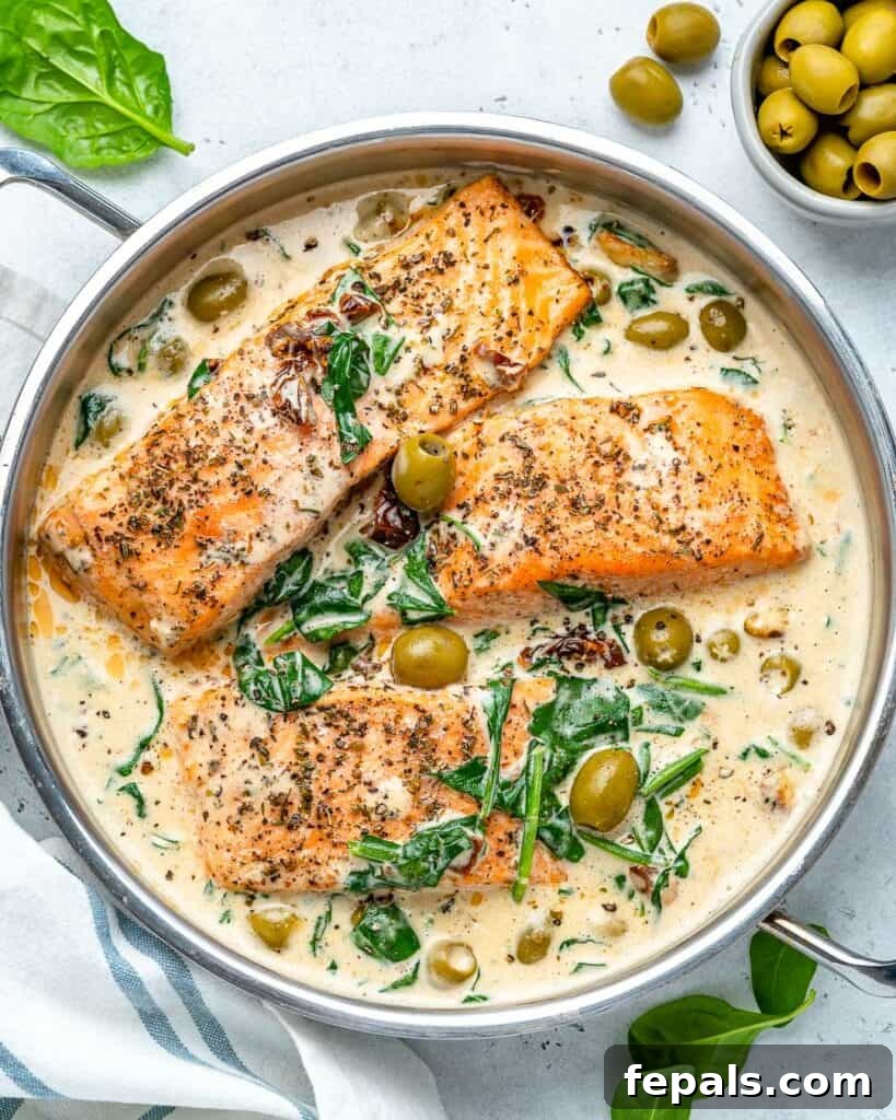 Salmon fillets perfectly cooked in a creamy Tuscan sauce in a large pan, showcasing the vibrant colors.