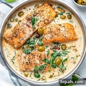 top view of Creamy Tuscan salmon fillets in pan in a creamy Tuscan sauce with spinach and olives