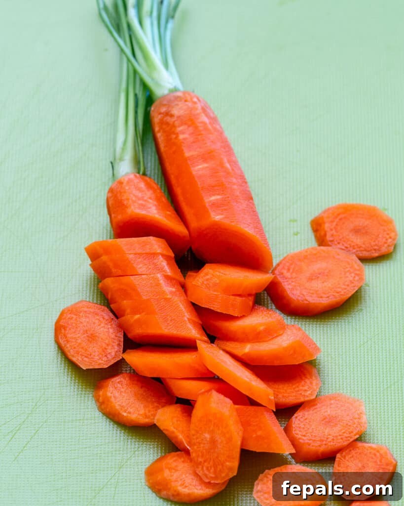 Carrots sliced neatly on a vibrant green cutting board, ready for soup.