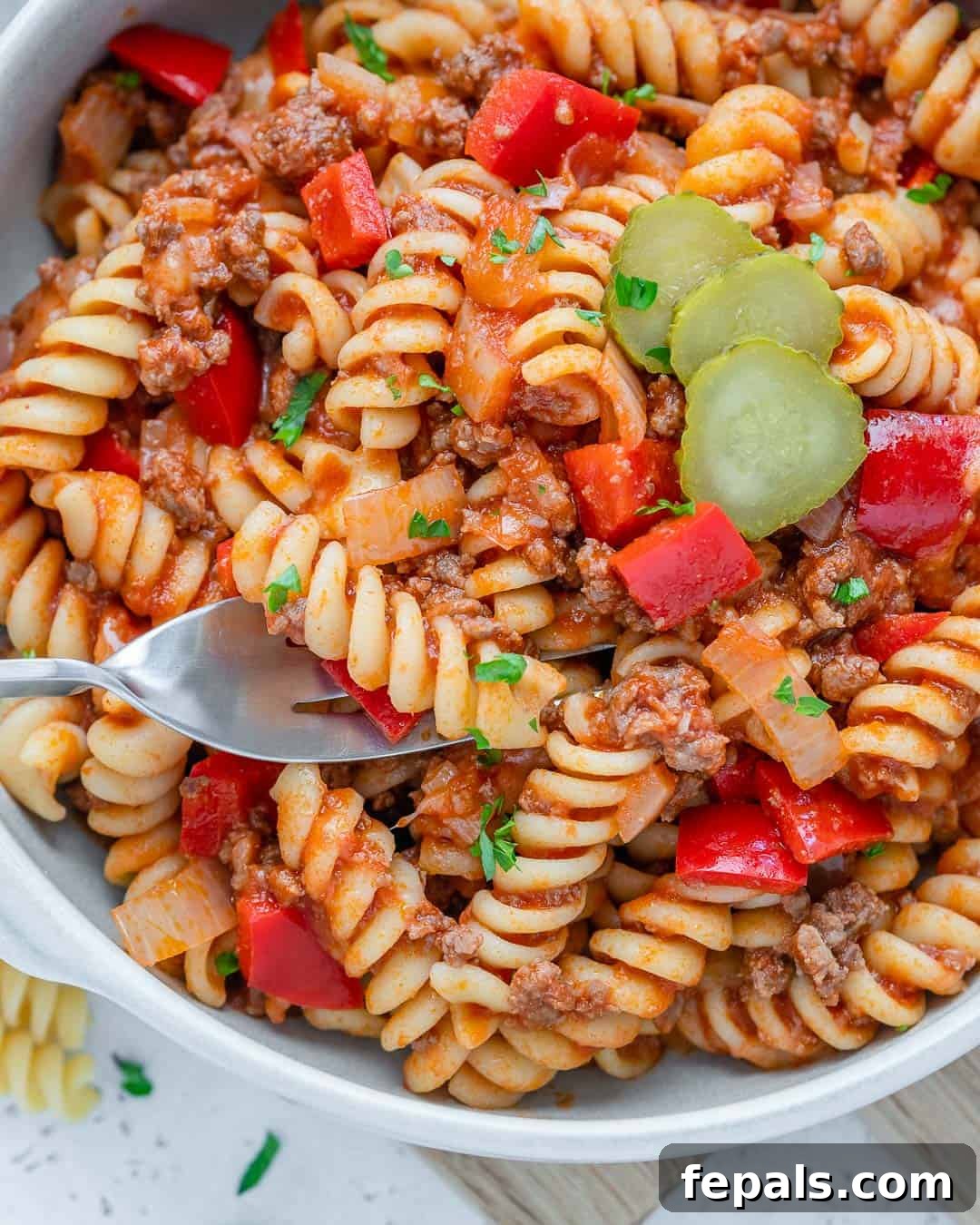One-Pot Cheeseburger Pasta 2 Rich and savory cheeseburger pasta in a white bowl with a fork, ready to be enjoyed.