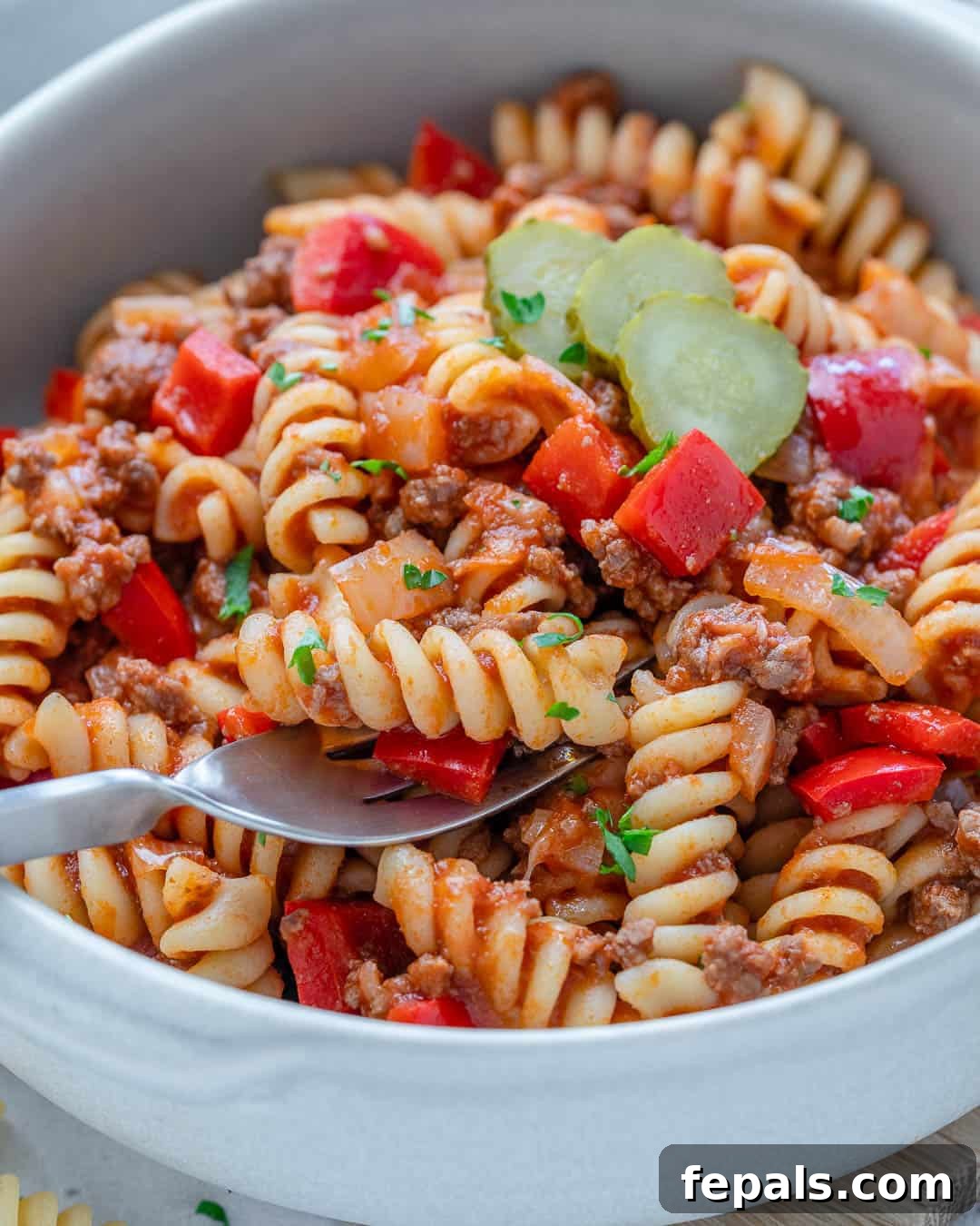 One-Pot Cheeseburger Pasta 6 A fork taking a delicious bite of cheeseburger pasta from a bowl.