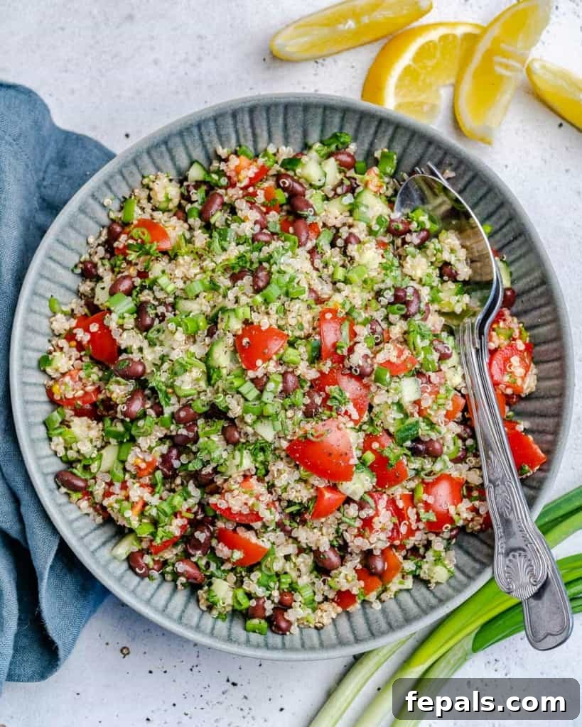 Vibrant Quinoa Black Bean Herb Bowl 4 top view of tabbouleh salad on a plate with lemon wedges and green onions on the side and spoon in the dish