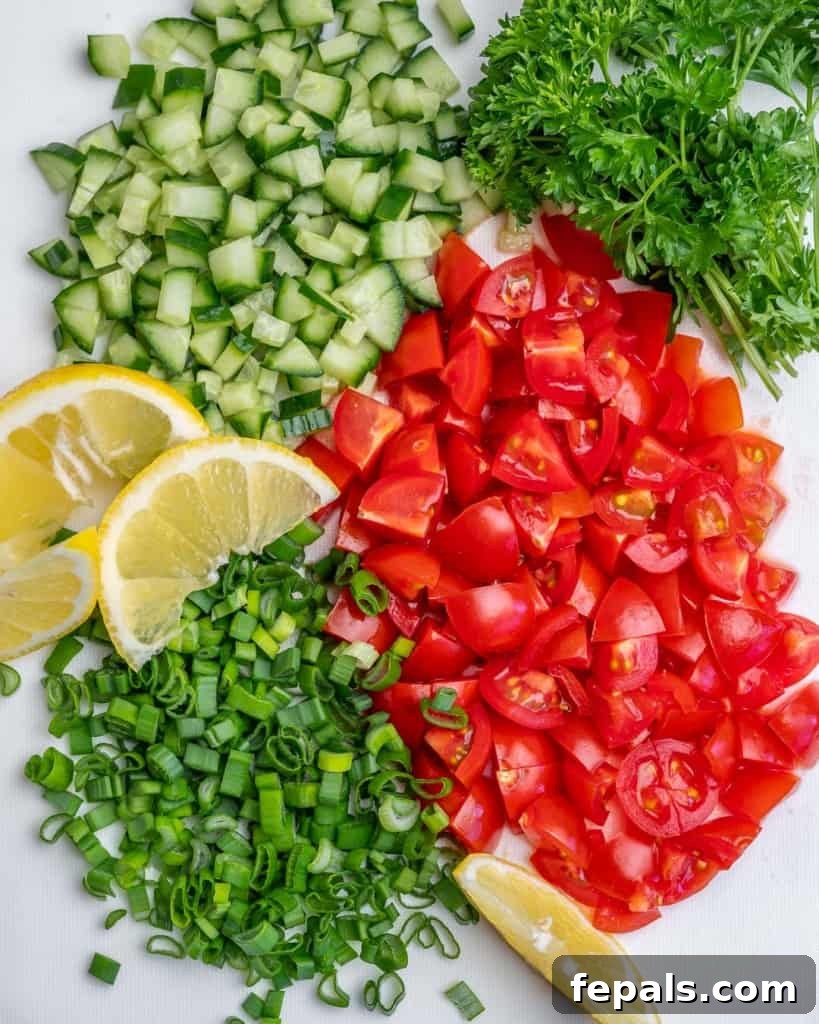 Vibrant Quinoa Black Bean Herb Bowl 6 tabbouleh salad ingredients. Chopped tomatoes, cucumber, parsley, and green onions. Lemon slices
