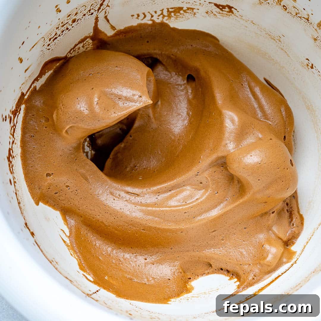 Close-up view of the perfectly formed, thick, and fluffy whipped coffee froth resting in a mixing bowl.